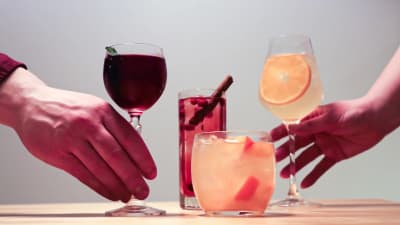 Neljä cocktailia, joita kaksi kättä ottamassa.