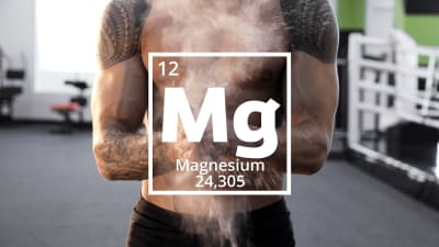 Den kemiska förkortningen för magnesium, Mg. En tatuerad manlig tyngdlyftare klappar ihpop händerna så att magnesiumpulver sprids i luften.