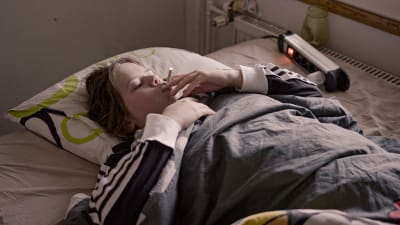 Tytöt 18 -dokumenttisarjan Aliisa makaa sängyllä ja polttaa tupakkaa.
