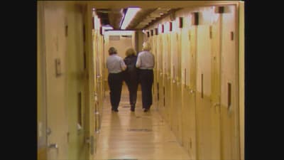 En kvinna följs av två poliser till en häktescell för tillnyktring år 1988.