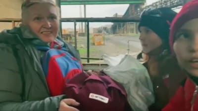 En kvinna och några barn som räddats i Mariupol har förts till en buss. 