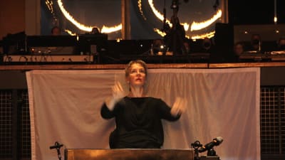 Susanna Mälkki ohjaa Kansallisoopperan montussa Ringin harjoituksia, taustalla tuliympyröitä.