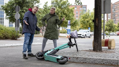 Jyrki Hakanen ja Hanna Kataja-Rahko paheksuvat huonosti parkkeerattua sähköpotkulautaa.