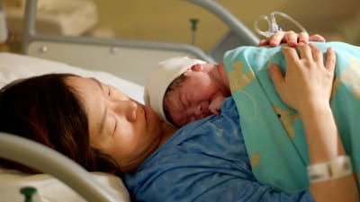 Chen ihastelee vastasyntynyttä vauvaansa Helsingin Naistenklinikalla.