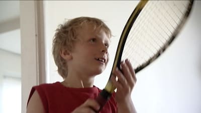 Nuori Emil Ruusuvuori pitelee tennismailaa edessään ja katsoo oikealle kamerasta.