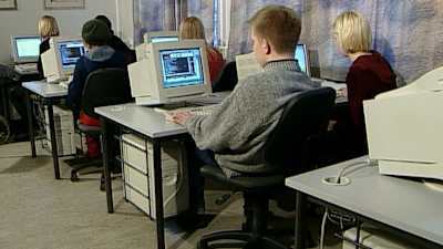 Joukko nuoria istuu tietokoneiden ääressä luokassa.