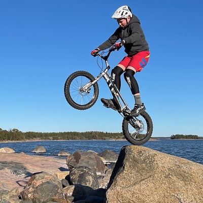 En kille gör trick med en cykel på klippor vid havet.
