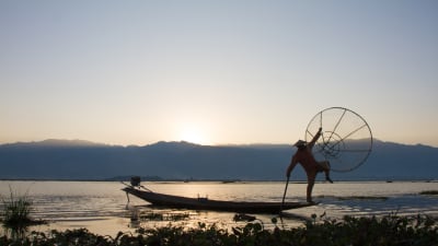 Burmesisk fiskare står i fören på båt