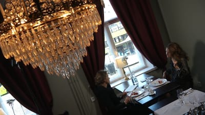 två kvinnor på café under kristallkrona