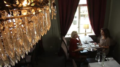 sofie asplund och pia-maria lehtola sitter på café under en kristallkrona