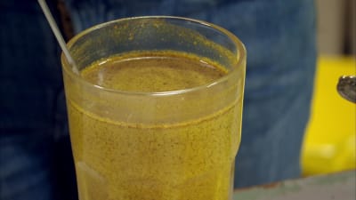 En gulbrund dryck kallad guldmjölk i ett glas