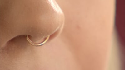 En septum piercing guldring i näsan.