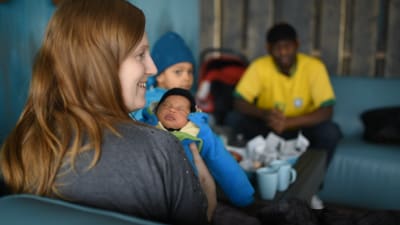 Lotten Walker med sin nyfödda bebi och familjen i bakgrunden