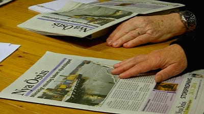Nya Östis ligger på bordet, chefredaktörens fingrar tummar på tidningen.