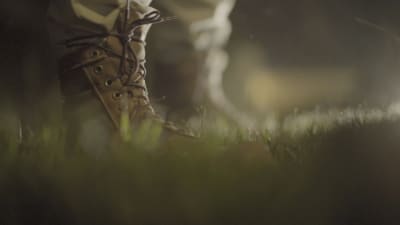 Nattlig bild av foten på en soldat som står på en gräsmatta.