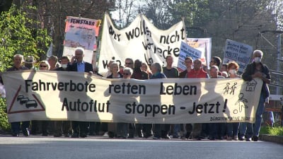 Demonstranter med ett lakan med texten "Fahrverbote retten leben autoflut stoppen - Jetzt!".