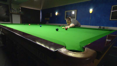 Snookerspelaren Heikki Niva stöter en boll på spelbordet.