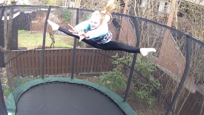 Flicka studsar högt i luften på trampolin