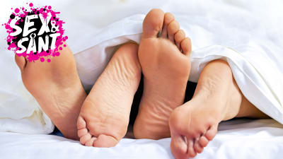 ett par av manliga och kvinliga fötter på varandra under vita lakan