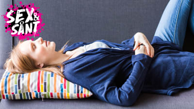 en vuxen kvinna som ligger på en soffa med sina händer placerade på sin nedre mage