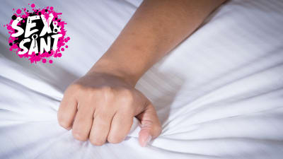 en hand som skrynklar lakanen i en säng