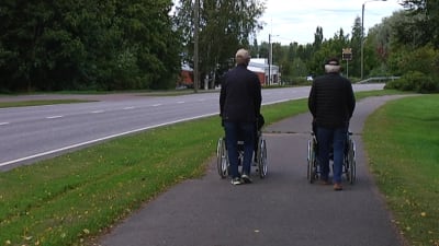 två personer skuffar rullstol