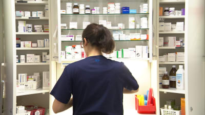 sairaanhoitaja jakaa potilaiden lääkkeitä sairaalan lääkekaapilla.