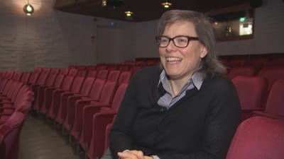 Författaren Lena Andersson sitter i en teatersalong och skrattar.