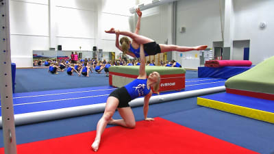 Akrobatiska gymnaster övar ett svårt lyft.