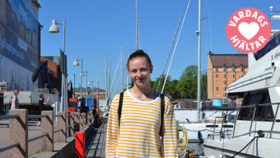 Emmy Nyström vid en strand framför några båtar.