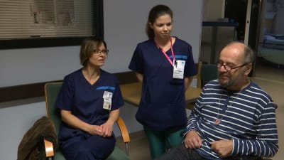 två personer ur sjukhuspersonal med klient i rullstol