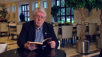 äldre man läser ur bok