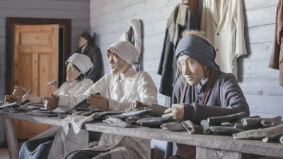 Tre uppstoppade dockor i ett museum, föreställer tre kvinnor i hucklen och förkläden som rensar sill.