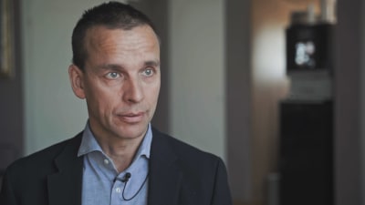 Stressläkare Markus Sundblom intervjuas på Eira sjukhus. Han är klädd i mörk kavaj och blå skjorta.