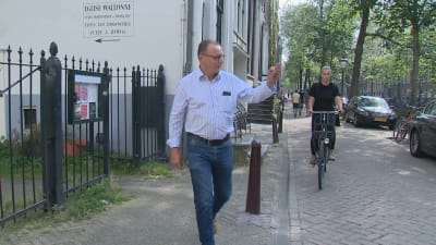 Invånaren Bert Nap vinkar åt en granne utanför sitt hus i De Wallen i Amsterdam. 