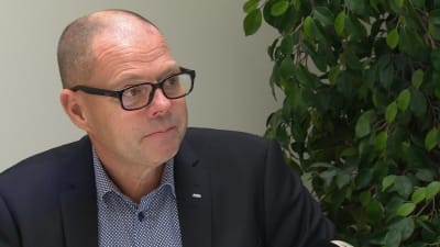 Christer Nyback, en man med kort hår, svarta glasögon och blå kavaj.