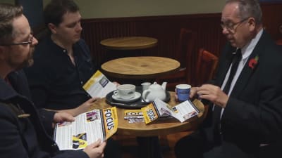 Liberaldemokratiska kandidaten John Skipworth planerar sin kampanj tillsammans med två medhjälpare. Skipworth är en man i senare medelåldern. Sällskapet sitter på ett café. 