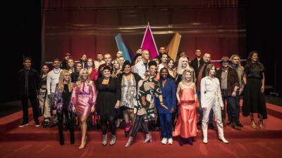 Alla 28 artister på rad med Melodifestivalens logga bakom sig.