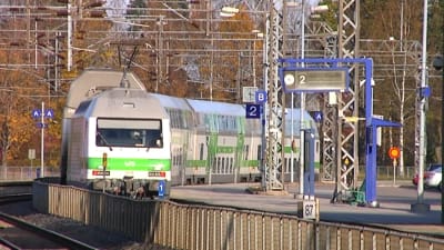 Ett grönt och vitt tåg åker iväg från perrongen.