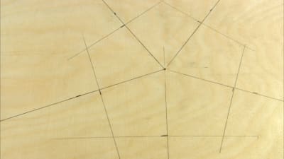 En pentagon ritad på trä.