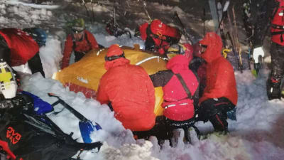 Österrikiska räddningsarbetare hjälper en man som begravdes i ett snöskred.