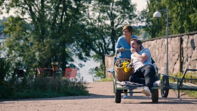 Maria Sundblom Lindberg skuffar Pelle heikkilä i kärra på ön Lonnan en solig sommardag.