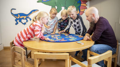 Lapset pelaa peliä lastentarhanopettajan kanssa.