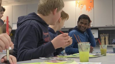 Venkat ler medan han pratar med de andra eleverna. 