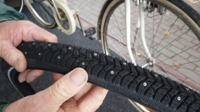En hand håller i cykeldäck för vinterbruk.