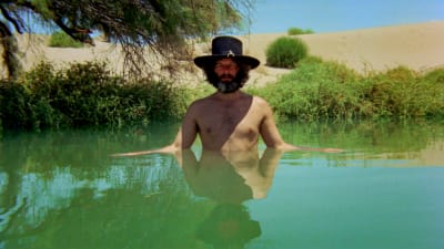 Mies seisoo aavikkolammessa hattu päässä. Kuva elokuvasta El Topo.