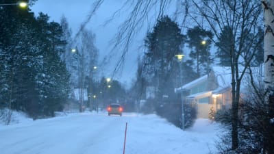 Snöstorm, bil kör på vägen, mycket snö, snön yr och blåser.