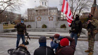 Beväpnade män ur Boogaloo-rörelsen står framför New Hampshires delstatsregeringsbyggnad i staden Concord.