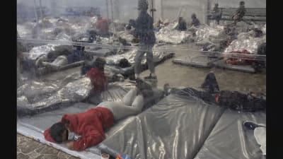 Minderåriga migranter ligger på plastmadrasser på ett stengolv