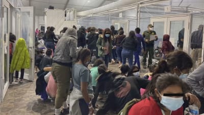 Tiotals migranter köar i ett trångt utrymme 